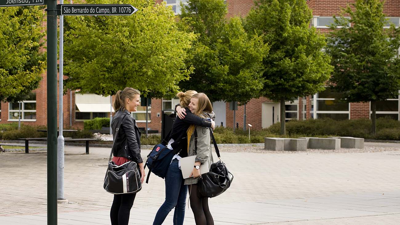 Bild på tre studenter som kramar varandra