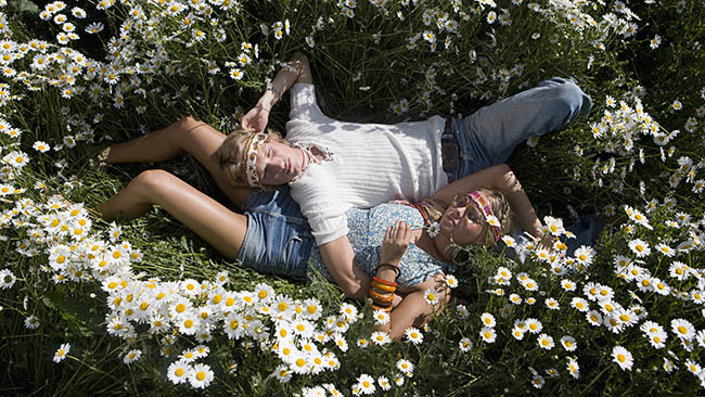 Ett ungt par ligger bredvid varandra på en blomsteräng