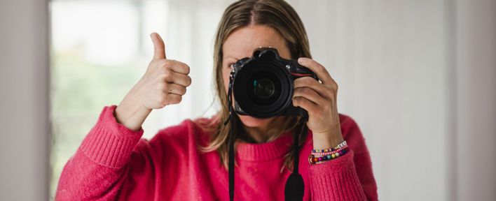 En kvinna tittar i kameran och gör tumme upp