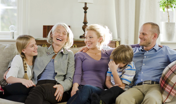 En familj sitter tillsammans i en soffa och skrattar.