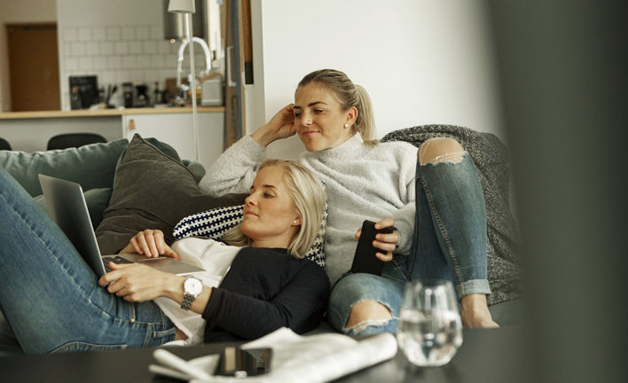 två tjejer hänger i en soffa och kollar på dator