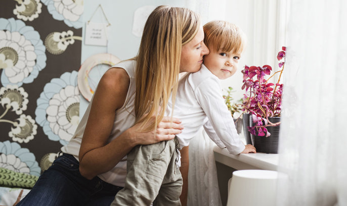 En mamma med sitt barn tittar ut genom fönster
