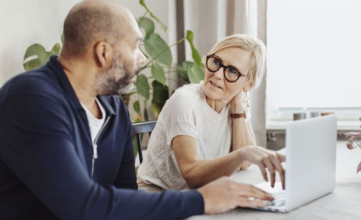 Ett par sitter vid köksbordet med en dator.